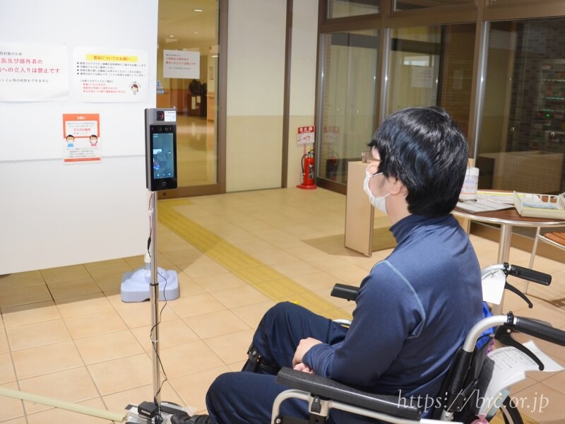 障害者支援施設にじに設置されたサーマルカメラで体温測定する利用者の男性